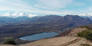 航拍:无人机飞越森林山谷湖，鸟瞰图上的阿尔卑斯雪山，晴朗的蓝天，都灵，意大利。
