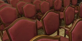 许多木制椅子的特写。戏院里一排排空椅子。镶花地板。