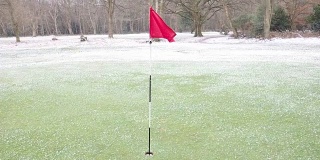 高尔夫球洞旗子在风和雪