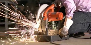 人们努力工作，锯着钢。工人使用刀圆金属有火花。工程，车间，工业，制造和商业的概念。