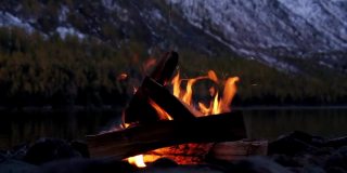 阿尔泰山脉下多恩斯科湖岸边的篝火在深夜，山上覆盖着雪