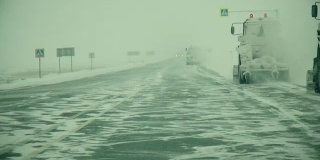 在大雪覆盖的西伯利亚路线上，汽车在一串卡车中行进，侧风阵阵