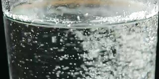 玻璃杯，水里放着泡腾片。在黑色