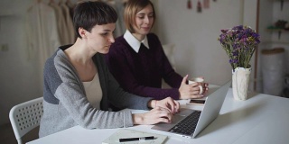 两个女学生坐在桌子旁，用笔记本进行在线教育