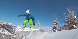 慢动作:专业滑雪板运动员骑着雪橇下坡，然后跳到空中。