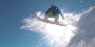 慢镜头:滑雪者在阳光明媚的山区的冬日里在粉雪中跳跃