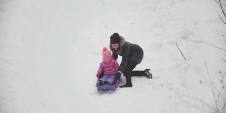 妈妈拉着雪橇，里面躺着她那滑稽的女儿