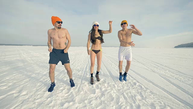 三个朋友穿着泳衣在寒冷的训练中又跳又跳。4 k。