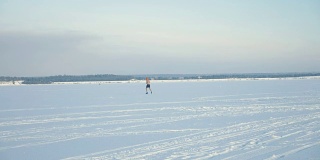一个赤裸上身的男人的剪影在远处冰冻的河上奔跑。4 k。