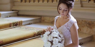 美丽的新娘在室内新娘礼服与花束和蕾丝面纱