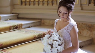 美丽的新娘在室内新娘礼服与花束和蕾丝面纱视频素材模板下载