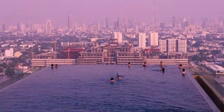 人们在游泳池游泳的时间流逝与城市景观和紫色天空的城市景观与紫外线的概念