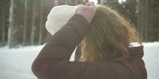 一个美丽的年轻女子在一个下雪的日子戴着一顶无檐帽的侧面照片