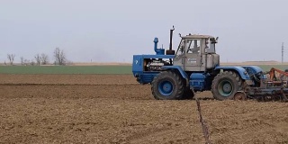 播种前要把地里的土壤弄松。拖拉机用犁犁地