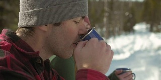 一个年轻的爱的夫妇喝一些热咖啡在一个下雪天的档案照片