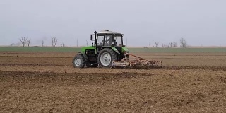 播种前要把地里的土壤弄松。拖拉机用犁犁地