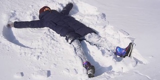 美丽的年轻女子在做雪天使