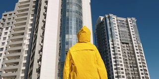 一个穿着黄色雨衣的人站在现代住宅区大楼前