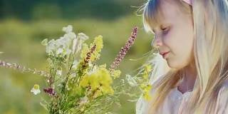 可爱的小女孩以绿色的风景为背景收集野花