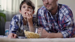 父亲抱着小儿子看电影，带着爆米花回家，为孩子感到骄傲视频素材模板下载