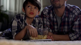 继父和儿子在家看电视到很晚，吃垃圾食品，亲密无间视频素材模板下载