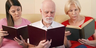 一对老年夫妇和十几岁的女儿在看纸质书。传统古典读本的概念