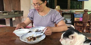 亚洲女性使用智能手机，在家吃午饭