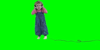 可爱的小女孩戴着大耳机在绿色背景上跳舞