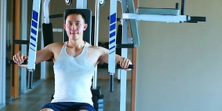亚洲男子尝试在健身房进行体重训练