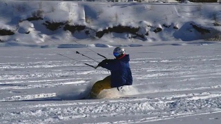 慢动作:一名男运动员正在滑雪板上放风筝。他在一个大湖的冰面上打滚。翻滚时，他会进行各种跳跃、动作和其他练习。雪板上的雪向不同的方向飞舞。视频素材模板下载