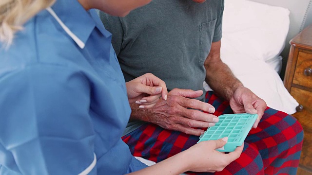 护士帮助老年人在家服药的特写