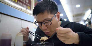 一名亚洲男子在餐厅吃香港汤面