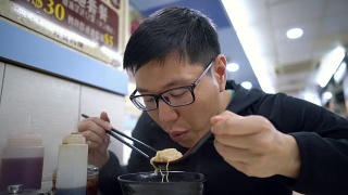 一名亚洲男子在餐厅吃香港汤面视频素材模板下载