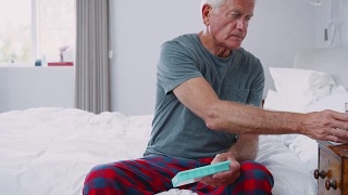 坐在家里的床上吃药的老人视频素材模板下载