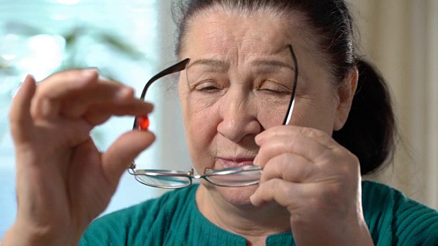 一位年长女性服用红色药片的特写