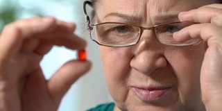 一位年长女性服用红色药片的特写