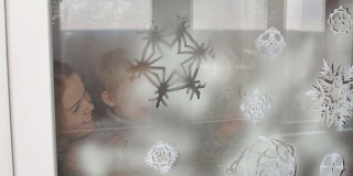 母亲和儿子用假雪装饰窗户。