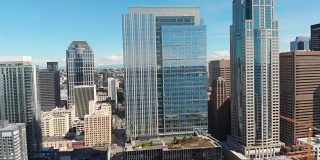 无人机拍摄飞行和平移在西雅图市中心的城市景观，华盛顿与建筑物，滨水，太空针，蓝天和高速公路在视野。