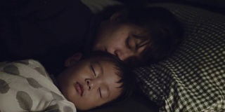 年轻的亚洲母亲在家里拥抱她的儿子。