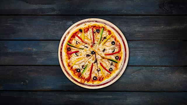 美味的披萨配蘑菇、鸡肉、甜椒和橄榄。在木架子上旋转。俯视图中心方向