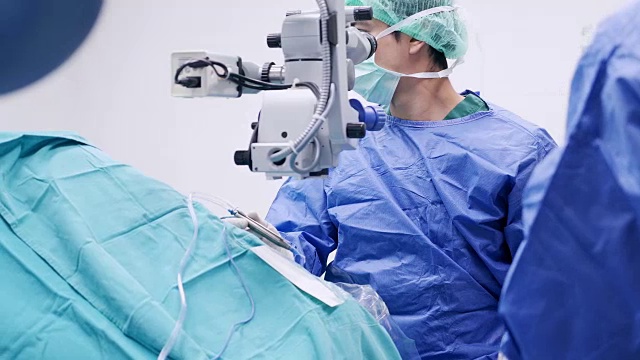 仪器护士为眼科医生增加手术工具和打字监视器触摸屏。眼科医生在他的诊所给病人做手术