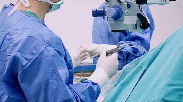仪器护士为眼科医生增加手术工具和打字监视器触摸屏。眼科医生在他的诊所给病人做手术