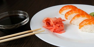 四个大的寿司和一片鲑鱼放在一个大盘子里。镜头对准