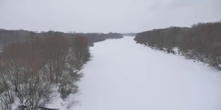 冬天的背景。冰封的河面上有芦苇和树木，冬季是俄罗斯户外大雪纷飞的自然景观