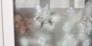 母亲和儿子用假雪装饰窗户。