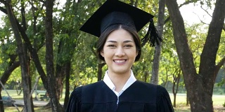 年轻的亚洲女学生戴着毕业帽和礼服，花园背景，女性与毕业概念。