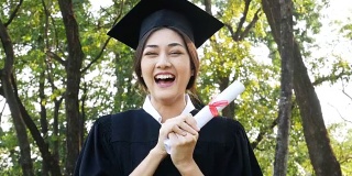 年轻的亚洲女学生戴着毕业帽和礼服，花园背景，女性与毕业概念。