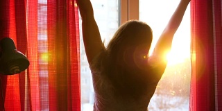 清晨，女孩站在窗前，拉开窗帘。阳光穿过玻璃，用晨光照亮房间。