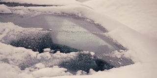一个年轻人在清理车窗上的雪
