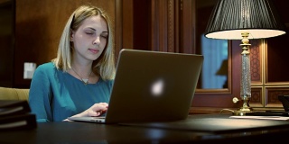 商务女性打开笔记本电脑工作的桌子上有台灯